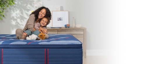 Woman and child sitting on a Posturepedic Elite Spring Pillow Top mattress