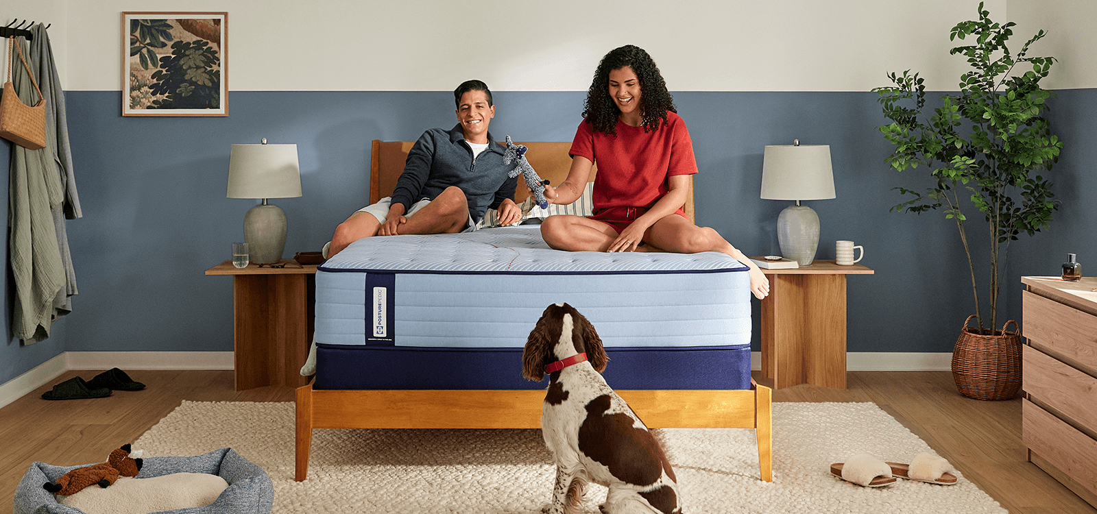 Couple laying on a Posturepedic Spring mattress playing with dog