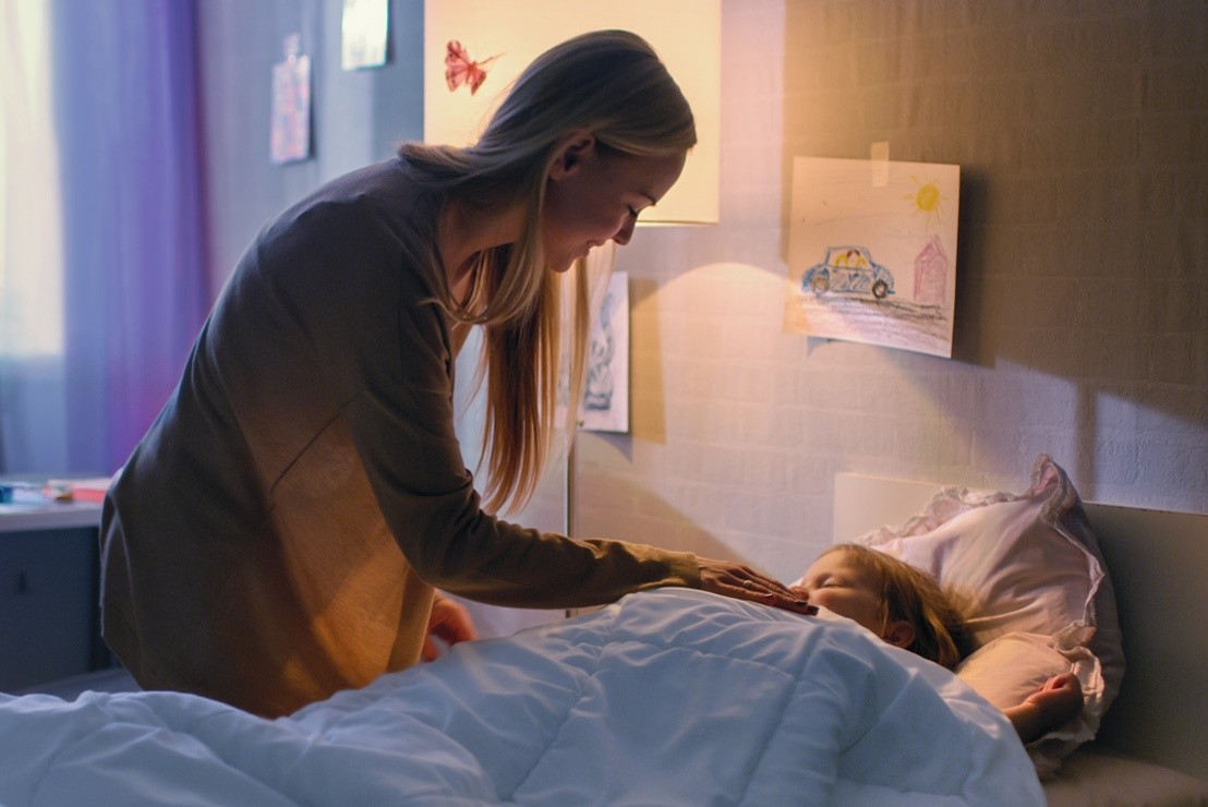 a parent tucking a child into bed